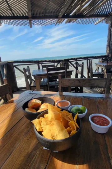 Table setting at Restaurant Villa Ortegas with nachos, dips, and a scenic ocean view.
