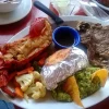 Dinner plate at Restaurant Villa Ortegas with lobster, steak, baked potato, and mixed vegetables.