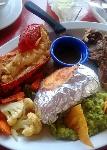 Dinner plate at Restaurant Villa Ortegas with lobster, steak, baked potato, and mixed vegetables.
